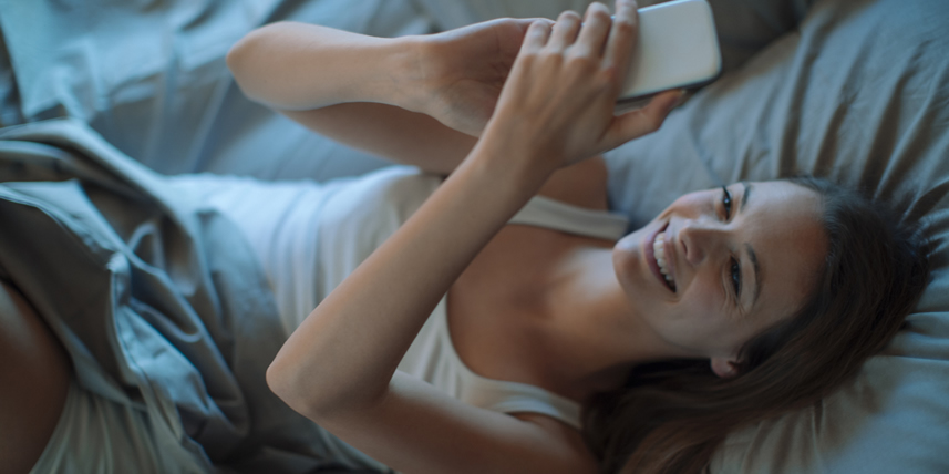 happy-woman-dating-by-mobile-phone-in-bed